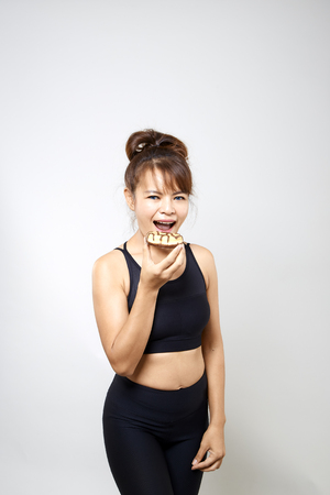 Young woman yoga holding donuts with junk food on white background, Concept healthy foodsの写真素材