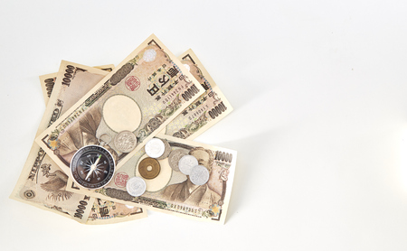Compass with Japanese yen banknotes and Japanese yen coin on white backgroundの写真素材
