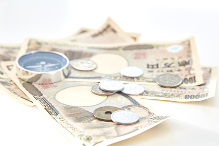 Compass with Japanese yen banknotes and Japanese yen coin on white backgroundの写真素材