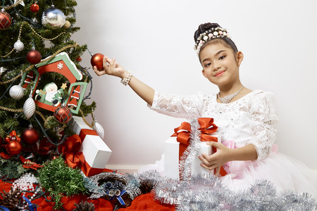 Merry Christmas and Happy Holidays Cute little child asian girl is decorating the Christmas tree indoors.の写真素材