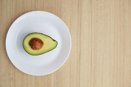 Healthy vegetarian, Avocado on white plate on Brown wood table.