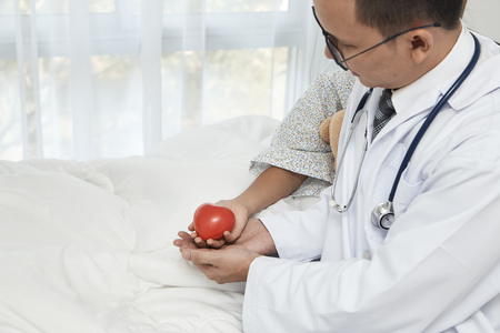 Care, Doctor with stethoscope holding red heart and kid girl in the patient room, Healthcare and medicine concept - Cancer girl awarenessの写真素材