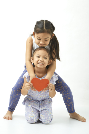 Portrait of two attractive girls Holding a heart-shaped paper of cute asian girl love on whiteの写真素材