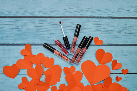 Kanchanaburi, Thailand, Jan 11, 2019 Queen Mom lipstick matte, Red hearts paper with Makeup products new lipstick matte on blue wooden background. Valentine's Day and Mother's Day. Copy space. Flat lay , Photography minimalのeditorial素材