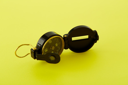 Close up Minimal Compass on bright yellow background , Concept of Travel above with copy space.の写真素材