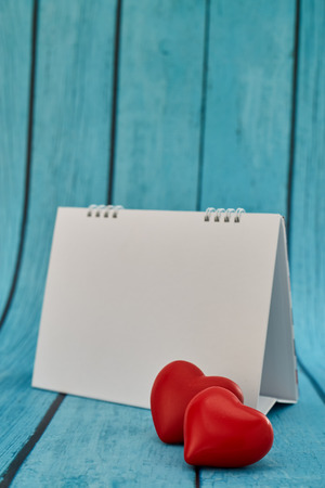 Heart and a empty calendar on bright blue wooden board for valentines day and love concept with copy space for textの写真素材