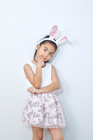 9 year old girl, Little asian girl in bunny ears studio isolated on bright gray wall easter  celebration holding pink tulips, spring and easter day backgroundの写真素材