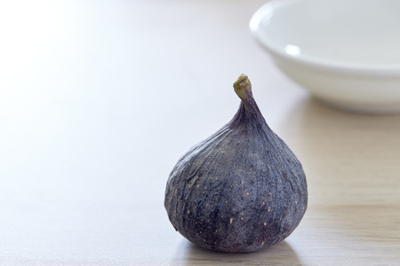 Fresh fig with plate on rustic Bright brown wooden backgroundの写真素材