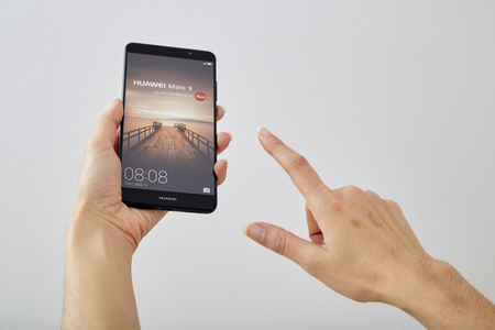 holding black smartphone Huawei Maet 9, Concept of communication and communicationのeditorial素材