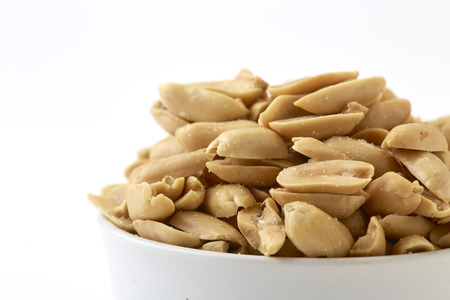 Small bowl of roasted salted peanuts on white background