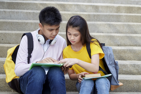 Two students guy and girl studying stairs in park of happy teen high school students outdoors