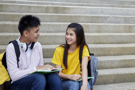 Two students guy and girl studying stairs in park of happy teen high school students outdoorsの写真素材
