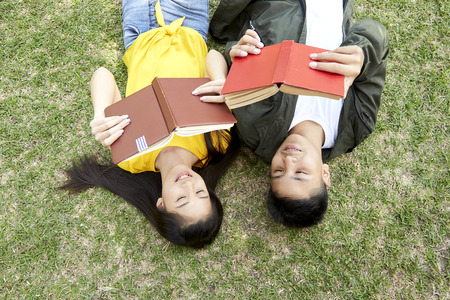 Back to school, Teenagers asian boy and girl happy students with books lying on green grass at school park, concept is happy with finding knowledge.の写真素材