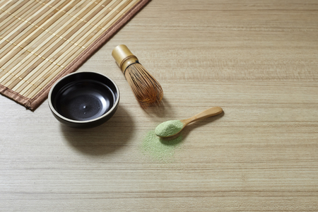 Powder organic matcha milk green tea in a spoon with bowl and bamboo whisk on wooden table, flat lay food, copy space for designの写真素材