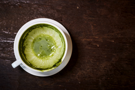 Empty white cup of matcha tea or green tea on wooden table after drink