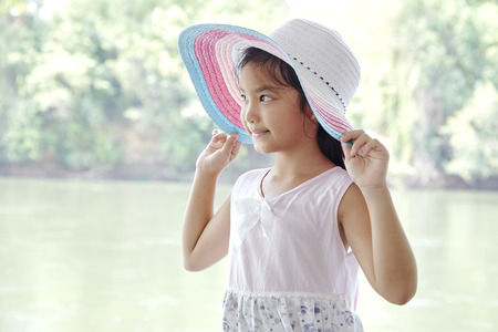 Happy Little Asian Girl outdoors in summer wear straw hatの写真素材