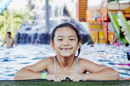 Smiling little asian girl at the edge of a swimming pool,  summer vacation conceptの写真素材