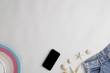 Summer holiday background, travel concept with seashells, hat and and tropical leaf and smartphone on white background , copy space. summer conceptの写真素材