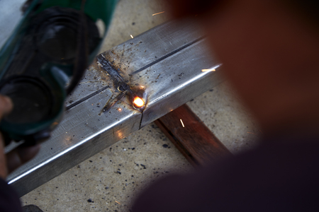 Asian man worker making sparks while welding steel