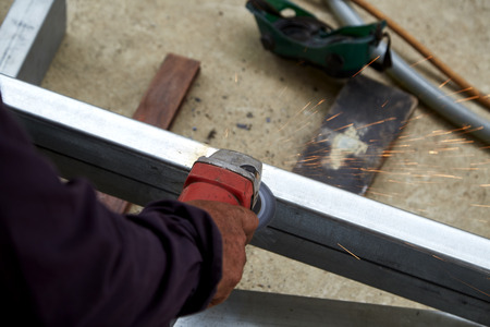 Hand Electric wheel grinding on steel structure in factory