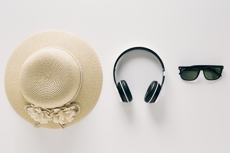 Summer holiday background, flat lay beach women's accessories: straw hat, headphones, sunglasses on white background, with empty space for text. Travel and fashion concept.の写真素材