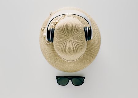 Summer holiday background, flat lay beach women's accessories: straw hat, headphones, sunglasses on white background, with empty space for text. Travel and fashion concept. Vacation summer sales.の写真素材