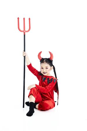 Little asian girl in a halloween fancy dress devil holding the trident and the blank board in a...