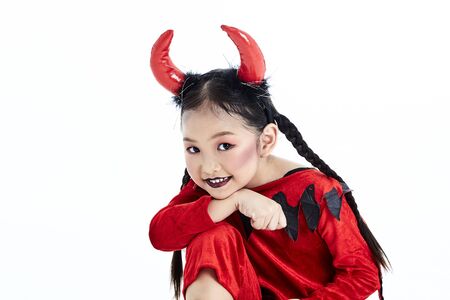 Little asian girl in a halloween fancy dress devil holding the trident and the blank board in a...