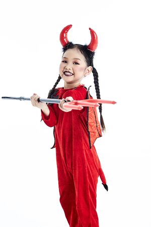 Little asian girl in a halloween fancy dress devil holding the trident and the blank board in a white studioの写真素材