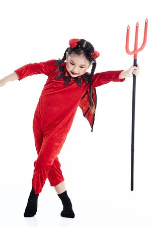 Little asian girl in a halloween fancy dress devil holding the trident and the blank board in a...