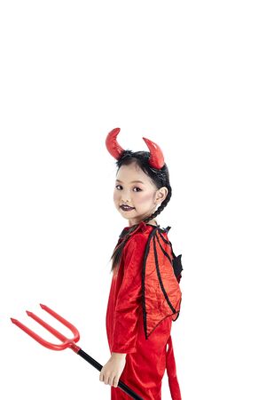 Little asian girl in a halloween fancy dress devil holding the trident and the blank board in a white studioの写真素材