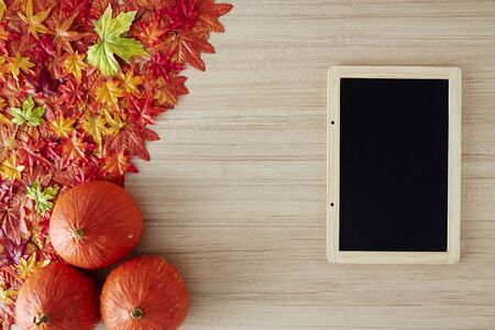 Autumn leaves and pumpkin on wooden background, copy space. Thanksgiving dayの写真素材