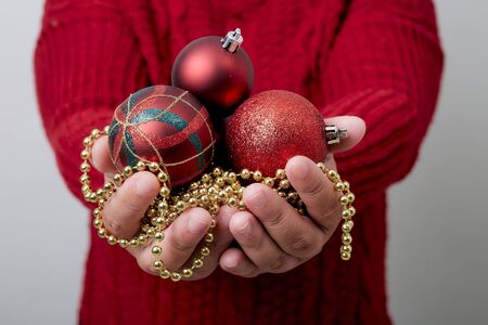 Female hands holding a Christmas balls bright gray background