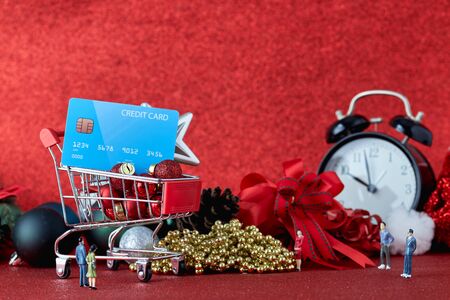 Miniature Shopping trolley with gift Christmas balls and  credit card on Defocused red lights background. Christmas and New Year sale, Online shopping Christmas, copy space for textの写真素材