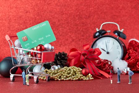 Miniature Shopping trolley with gift Christmas balls and  credit card on Defocused red lights background. Christmas and New Year sale, Online shopping Christmas, copy space for textの写真素材