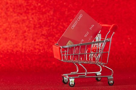 Mini supermarket trolley with credit card against on defocused red background,  cradit card in shopping, Online shopping concept, copy space for textの写真素材
