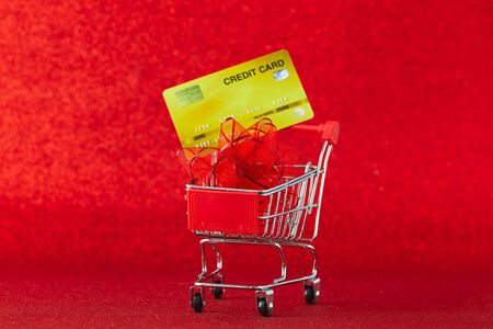 Mini supermarket trolley with credit card against on defocused red background,  cradit card in shopping, Online shopping concept, copy space for textの写真素材