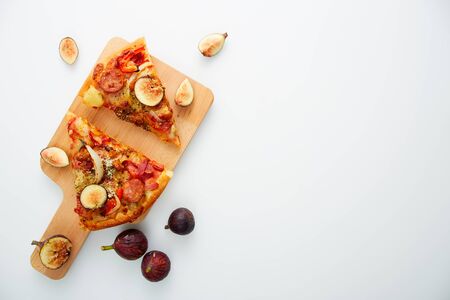 Flat lay. Slicing Pizza with figs a wood cutting board on table white, copy space for textの写真素材