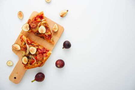Flat lay. Slicing Pizza with figs a wood cutting board on table white, copy space for textの写真素材