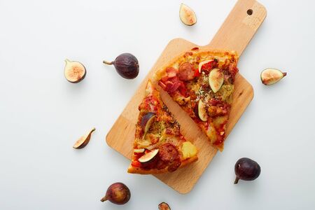 Flat lay. Slicing Pizza with figs a wood cutting board on table white, copy space for text