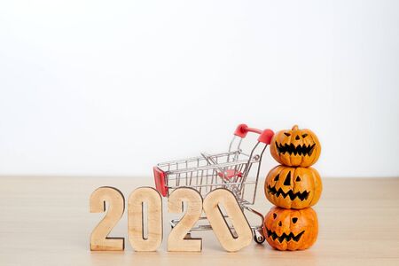 Halloween 2020 festival shopping concept. Halloween pumpkins with shopping cart on wood backgroundの写真素材