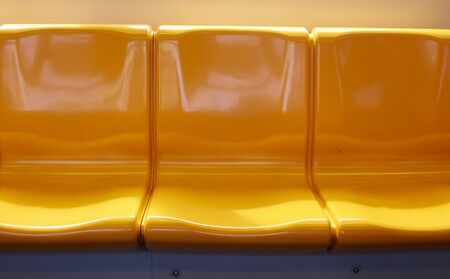 The yellow chair rows on the skytrain in Thailand are empty.
