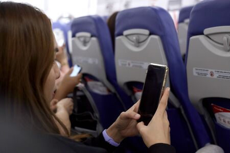 Close-Up Of Woman Using Phone While Traveling In Airplaneのeditorial素材