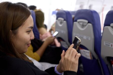 Close-Up Of Woman Using Phone While Traveling In Airplaneのeditorial素材