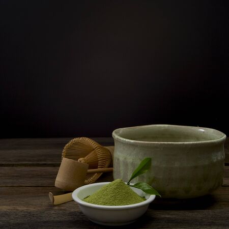 Green Matcha tea bamboo whisk in a bowl on wooden Preparation of powdered green tea