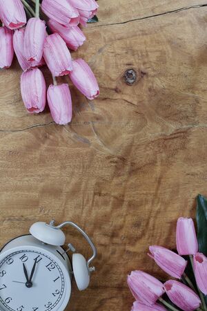 Alarm clock with beautiful bouquet of tulips flower on wooden