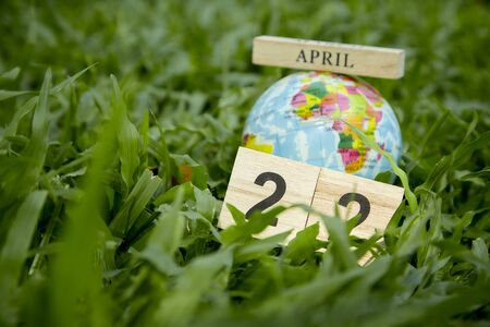 22 April Earth Day Concept, Globe lies on green grass field background textured for banner designの写真素材