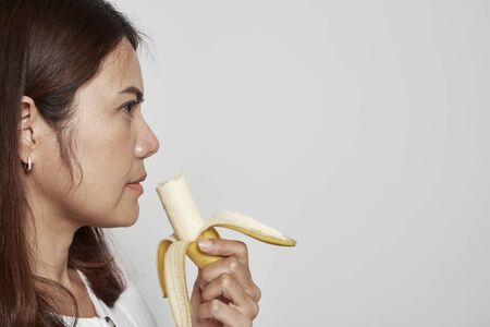 Young asian woman holding bananaの写真素材