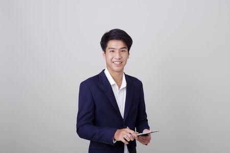 Attractive young businessman architect in stylish suit holding notes clipboard on white background, Architectural, engineering, construction and home design concept.の写真素材