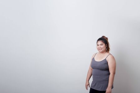 Beautiful fashionable plump asian woman in exercise clothes standing on isolated bright grey background, Healthy exercise conceptの写真素材